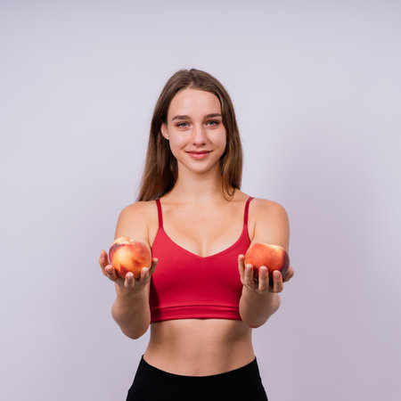 Happy cheerful a young blond woman holding nectarines in handsの写真素材
