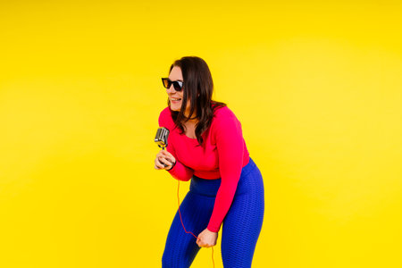 Smiling brunette woman with microphone on a colored studio backgroundの写真素材