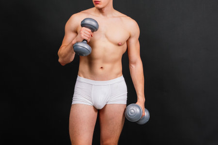 Body, dumbbell and workout with sports man in studio isolated on black background for health or wellness. Exercise, muscle or weight training with shirtless and strong athlete in dark for fitnessの写真素材
