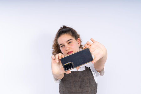 Happy beautiful young woman teenager with a long curly hair holding mobile phone