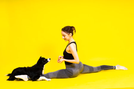 Shot of female in leggings with a border collie dog isolated on yellow backgroundの写真素材