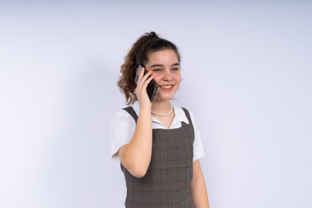 Happy beautiful young woman teenager with a long curly hair holding mobile phone