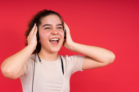 Sport fitness teenager girl with a headphones on red backgroundの写真素材