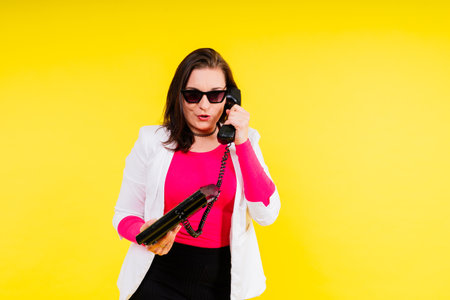 Photo portrait of female holding a phone isolated on yellow backgroundの写真素材