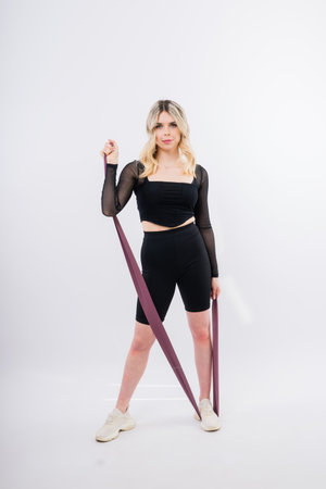 Woman in a black sports clothes exercising with resistance band in studio.の写真素材