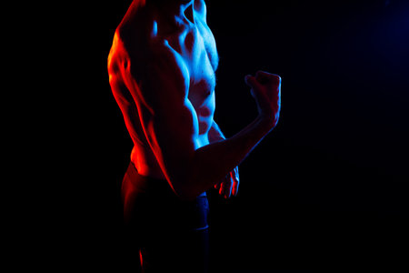 Image of muscle man posing in a studio, dark white red backgroundの写真素材