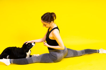 Shot of sport female in leggings with a border collie dog isolated on yellow and red backgroundの写真素材