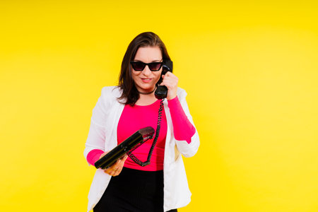 Photo portrait of female holding a phone isolated on yellow backgroundの写真素材