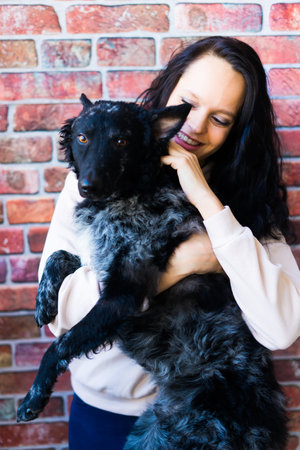 Happy brunette lady in a casual wear hugging pet dog.の写真素材