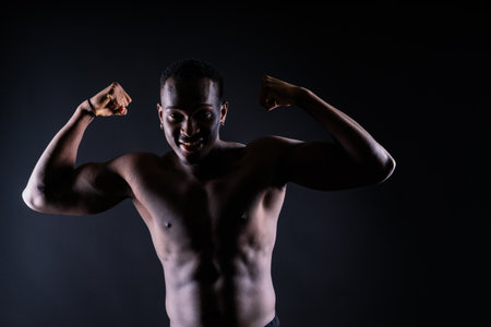Flexing, body and African man with muscle for exercise, workout goal and sport training in studio.の写真素材