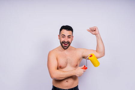 Young employee handyman using paint roller isolated on a background studio.の写真素材