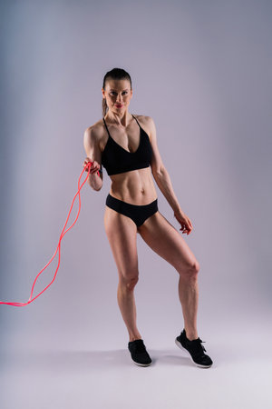Fitness woman doing jumping exercises with a skipping rope on colorful yellow red background.の写真素材