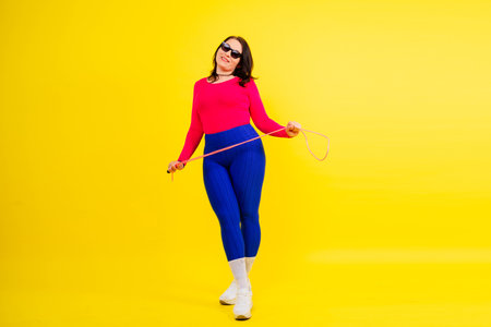 Smiling female in a sporty top and leggings holding jumping rope in handsの写真素材
