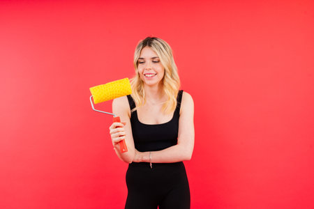 Excited female builder. Painter with a painting brush tool or paint roller.の写真素材