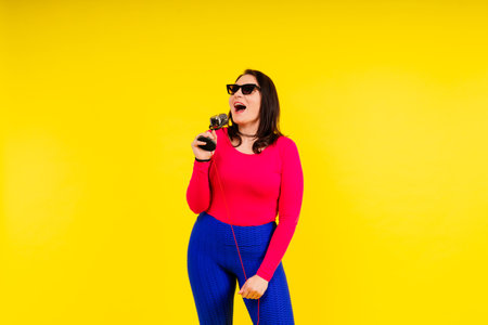 Smiling brunette woman with microphone on a colored studio backgroundの写真素材