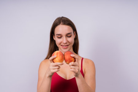 Fresh and sweet peaches fruit, a studio portrait of happy young woman, smilingの写真素材