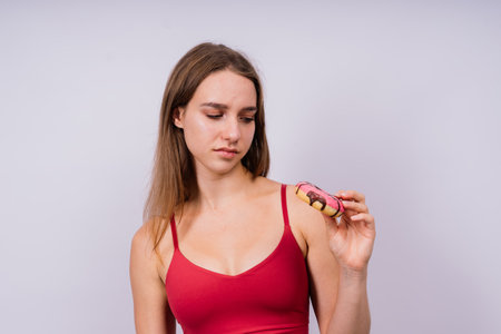 Lovely young caucasian woman in a sports wear with donuts on grey and yellow studio background.の写真素材