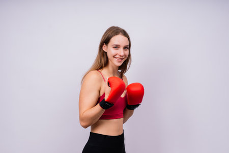 Young woman in a sportswear and boxing gloves standing isolated on white background.の写真素材
