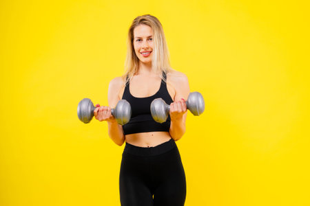 Sporty female working out with dumbbells. Photo of woman in sportswear, studio shotの写真素材