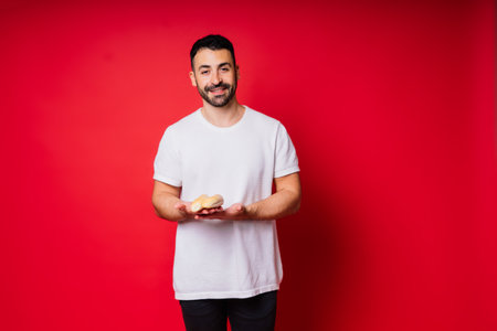 Man with freshly baked bread in hands isolated on red background studioの写真素材