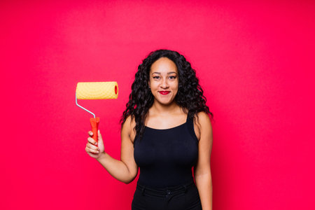 Happy young woman with paintroller, toothy smile during home renovation