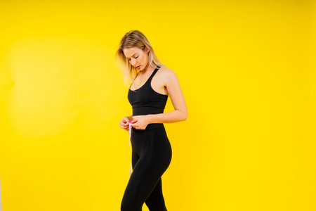 Smiling slim woman measuring her waist with tape. Fit young lady perfect shape, happy with her bodyの写真素材