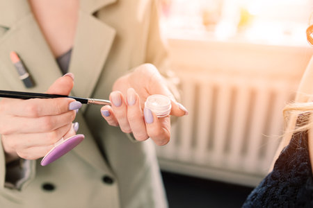 Makeup artist applies lipstick. Hand of make-up master, painting lips of young beauty model.の写真素材