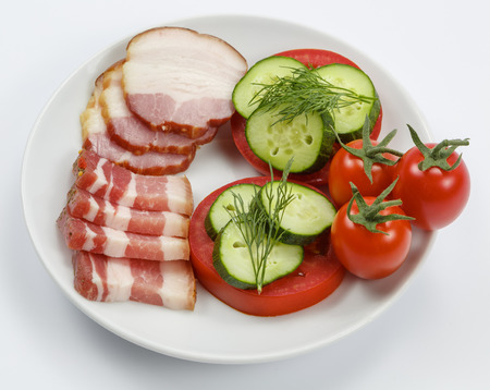 Slices of bacon with tomatoes and cucumbers on white backgroundの写真素材