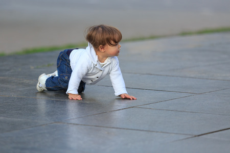 Little girl crawls on marble slabs outdoors in summerの写真素材