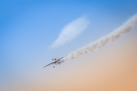 Light aeroplane flies down leaving behind itself a dark smoke as an illustration of a crash of a...