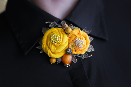 Brooch of handwork consisting of two yellow cloth flowers is attached to a black woman shirtの写真素材