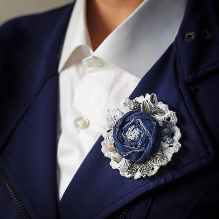 Brooch handmade in the form of a flower from denim as additional accessory of a woman business suitの写真素材