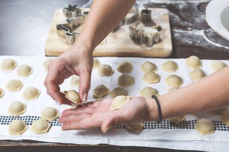The process of making delicious homemade dumplings. Female hands are laying out the just made dumplings on the tableの写真素材
