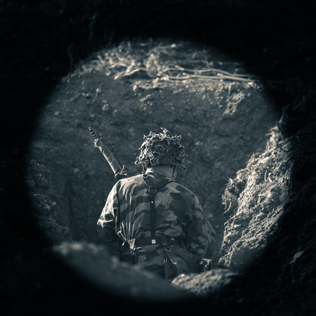 Soldier, dressed in camouflage uniform, stands in the trench. View from the back