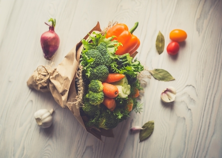 Bouquet of fresh vegetables on a white wooden table. The beach is a red onion, tomatoes, garlic, bay leaf. View from above. Toned imageの写真素材