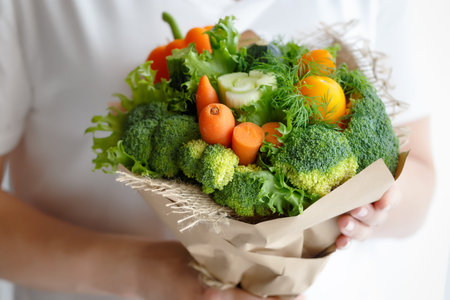 Bouquet of broccoli, celery, carrots, paprika and lettuce in the hands of a womanの写真素材
