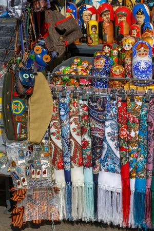 Russian souvenirs such as colorful shawls, scarves, painted matryoshkas, decorative small bags, purses and military headgear lie on the counter and wait for foreign touristsのeditorial素材