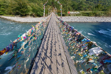 Long pedestrian suspension bridge across the mountain river Bzyb, in Abkhaziaの写真素材