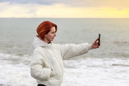 Young woman makes a selfie on the background of the seaの写真素材