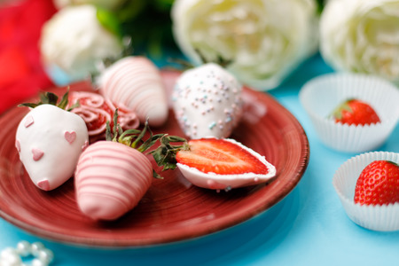 Ripe strawberries in white chocolate glaze lies on a burgundy plate on a turquoise backgroundの写真素材