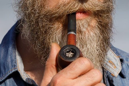 Bearded man holding a smoking pipe