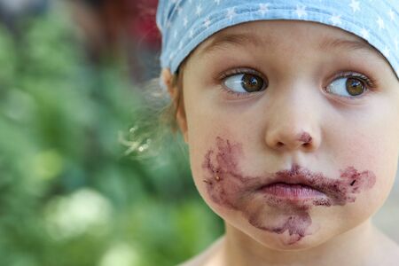 Portrait of a cute girl with a grimy mouth after eating mulberry berriesの写真素材