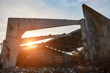 Concrete beams and walls of the destroyed old warehouse in the rays of the rising sun.の写真素材