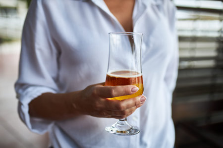 Glass of tasty light beer in the hand of a young woman.