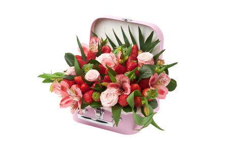 Unusual gift in the form of a pink suitcase filled with roses, orchids and ripe strawberries on a white background.の写真素材