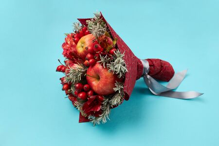 Unique gift in the form of a red bouquet of flowers and fruits on a blue background.の写真素材