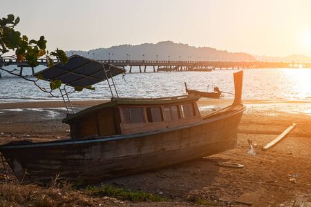 Small wooden boat lies on the shore due to the low tide early morning.の写真素材