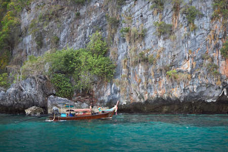 Phuket, Thailand, February 04, 2020: A small Thai boat sails tourists near a huge island.のeditorial素材