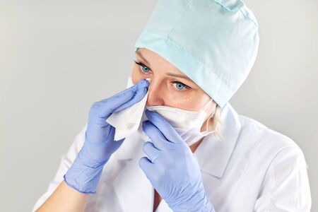 Tired female doctor wipes sweat from his face with a napkinの写真素材