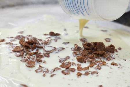 Fresh milk is poured onto a frozen metal surface as the basis for making homemade ice cream.